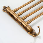 Antique brass wall mounted towel rack with folding arms and decorative hook for bathroom